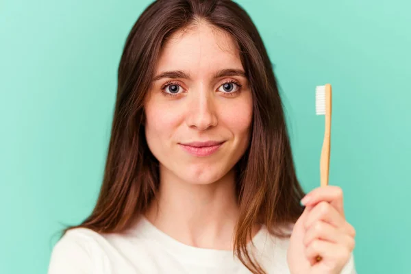 青い背景に隔離された歯ブラシを持っている若い白人女性 — ストック写真