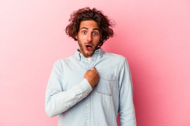 Pembe fırında izole edilmiş genç beyaz adam parmağını göstererek şaşırdı ve gülümsedi..