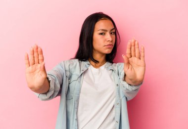 Genç Venezuelalı bir kadın pembe arka planda izole edilmiş elini uzatmış, dur işaretini gösteriyor, seni engelliyor..