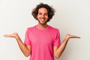 Beyaz arka planda izole genç beyaz adam kollarıyla ölçek yapar, mutlu ve kendinden emin hisseder..