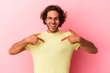 Pembe fırında izole edilmiş genç beyaz adam parmağını göstererek şaşırdı ve gülümsedi..