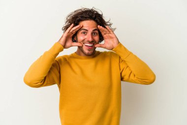 Beyaz arka planda izole genç beyaz adam hoş bir sürpriz alıyor, heyecanlı ve el kaldırıyor..