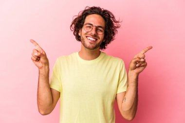 Pembe fırında izole edilmiş genç beyaz adam farklı fotokopi alanlarını gösteriyor, birini seçiyor, parmaklarıyla gösteriyor..