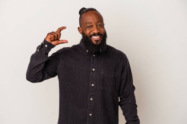 Pembe arka planda sakallı Afrikalı Amerikalı bir adam. Elinde küçük bir işaret parmağı olan, gülümseyen ve kendinden emin bir şey tutuyor..