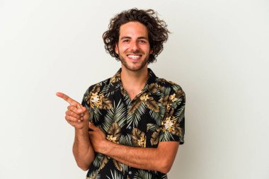 Beyaz arka planda izole edilmiş genç beyaz adam işaret parmağıyla işaret ederek gülümsüyor..