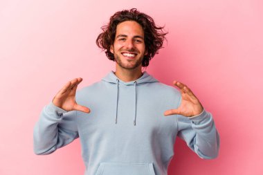 Kafkasyalı genç bir adam pembe fırında izole edilmiş. Elinde avuç içi olan bir şeyle kameraya sunuyor..