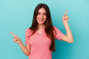 Mavi arka planda izole edilmiş genç beyaz kadın farklı kopya alanlarını gösteriyor, birini seçiyor, parmaklarıyla gösteriyor..
