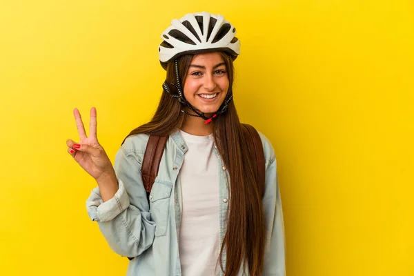 若いです学生Caucasian女性身に着けていますAバイクヘルメット絶縁上の黄色の背景ショーナンバー2とともに指 — ストック写真