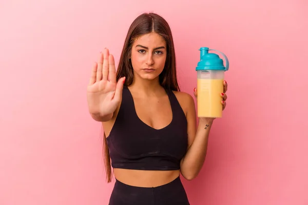 黄色の背景にタンパク質の揺れを持っている若い白人女性は あなたを防ぐために 停止記号を示す手を伸ばして立って — ストック写真