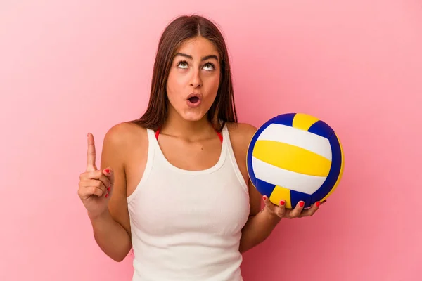 年轻的高加索女人拿着一个用粉色背景隔开的排球球 指向上方 张着嘴 — 图库照片