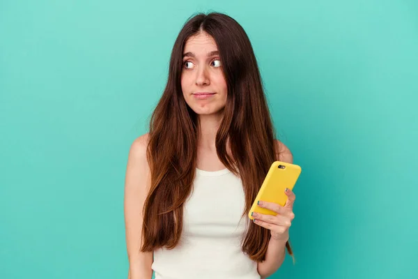 Ung Kaukasiska Kvinna Som Håller Mobiltelefon Isolerad Blå Bakgrund Förvirrad — Stockfoto