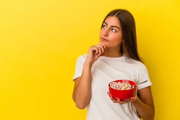 Mulher Caucasiana Jovem Segurando Cereais Isolados Fundo Amarelo Olhando Para — Fotografia de Stock