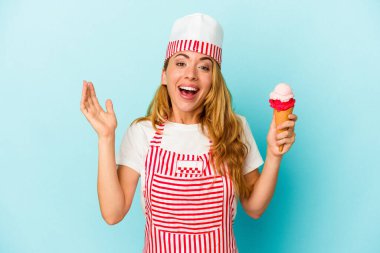Kafkasyalı dondurma üreticisi kadın mavi arka planda izole edilmiş bir dondurma tutuyor. Hoş bir sürpriz alıyor, heyecanlı ve el kaldırıyor..