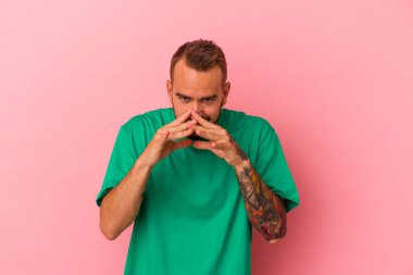 Pembe arka planda dövmeleri olan genç beyaz bir adam. Kafasında bir plan kuruyor..