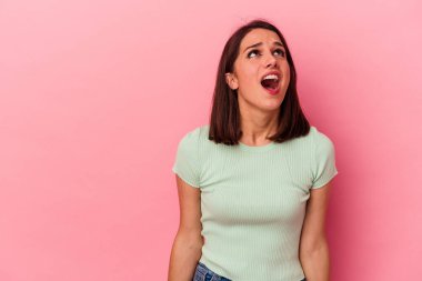 Pembe arka planda izole edilmiş genç beyaz kadın çok kızgın, öfkeli, hayal kırıklığına uğramış.