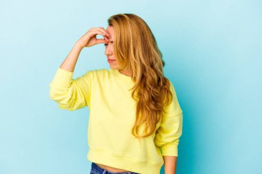 Kafkasyalı bir kadın mavi arka planda izole edilmiş, başı ağrıyor, yüzüne dokunuyor..