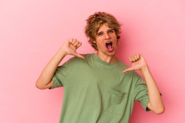 Pembe arka planda soyutlanmış beyaz makyajlı genç bir adam gururlu ve kendinden emin hissediyor, örnek olarak..