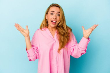 Beyaz kadın mavi arka planda izole edilmiş, gökyüzüne haykırıyor, yukarı bakıyor, hayal kırıklığına uğramış..