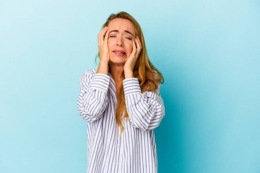 Beyaz kadın mavi arka planda izole edilmiş, ağlıyor, bir şeyden memnun değil, acı ve kafa karışıklığı kavramı..