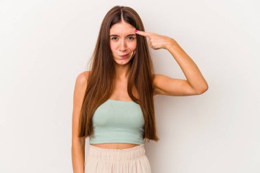 Beyaz arka planda izole edilmiş beyaz tenli genç bir kadın şakağı parmağıyla işaret ediyor, düşünüyor ve bir göreve odaklanıyor..