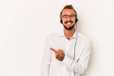 Beyaz arka planda izole edilmiş dövmeleri olan beyaz pazarlamacı genç adam gülümsüyor ve boş alanda bir şeyler gösteriyor..