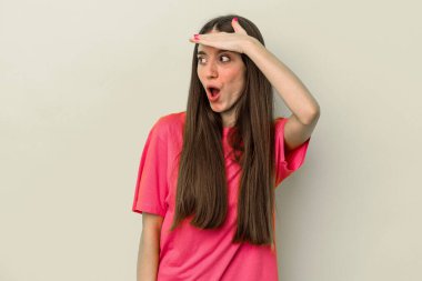 Sarı arka planda izole edilmiş, elini alnına koyan genç, beyaz bir kadın..