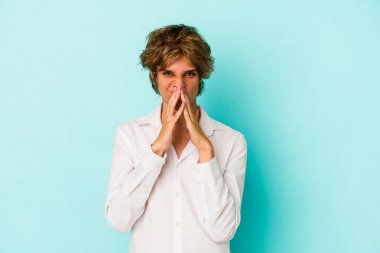 Kafkasyalı genç bir adam mavi arka planda izole edilmiş bir plan yapıyor, bir fikir kuruyor..