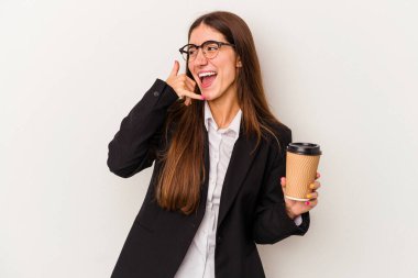 Beyaz arka planda izole edilmiş kahve içen Kafkasyalı genç iş kadını parmaklarıyla bir cep telefonu hareketi gösteriyor..