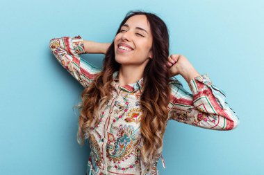 Mavi arka planda izole edilmiş genç Meksikalı kadın kollarını uzatıyor, rahat pozisyonda..