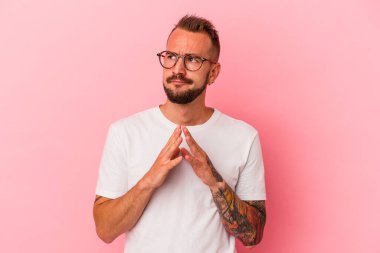 Pembe arka planda dövmeleri olan genç beyaz bir adam. Kafasında bir plan kuruyor..