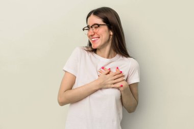 Sarı arka planda izole edilmiş genç beyaz kadın gülüyor, elini yüreğine koyuyor, mutluluk kavramını koruyor..