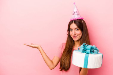 Pembe arka planda izole edilmiş bir doğum gününü kutlayan beyaz bir kadın bir avuç içinde fotokopi alanı ve belinde başka bir el tutarken görülüyor..