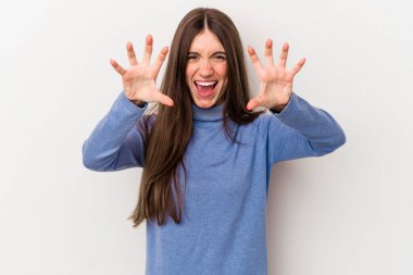 Beyaz arka planda izole edilmiş genç beyaz kadın pençelerini kedi taklidi yaparken gösteriyor, agresif bir hareket..