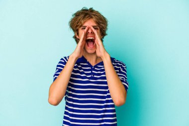 Makyajlı beyaz bir adam mavi arka planda izole edilmiş ve heyecanlı bir şekilde bağırıyor..