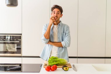Genç melez adam öğle yemeği için salata hazırlıyor rahatlamış bir şekilde fotokopi odasına bakıyor..