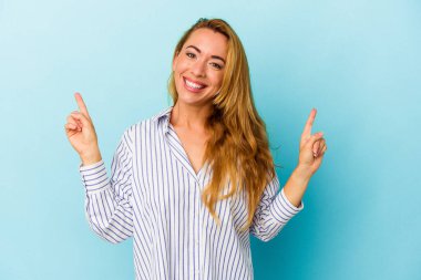 Mavi arka planda izole edilmiş beyaz kadın iki ön parmağı da boş bir alan gösteriyor..