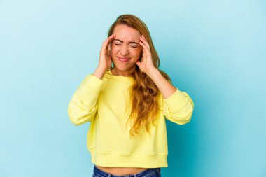 Beyaz kadın mavi arka planda izole edilmiş tapınaklara dokunuyor ve baş ağrısı çekiyor..