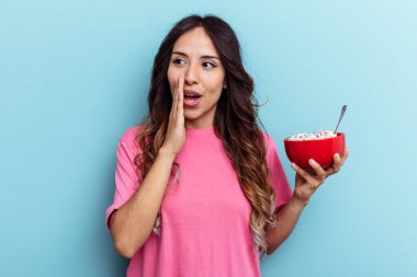 Mavi arka planda saklanmış mısır gevreği kasesi tutan genç bir ırk kadını gizli bir sıcak fren haberinin olduğunu söylüyor.