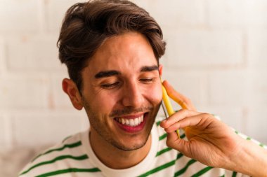 Genç melez adam koltuğunda telefonla konuşuyor.