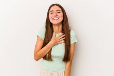 Beyaz arka planda izole genç beyaz kadın yüksek sesle gülüyor elini göğsüne koyuyor..