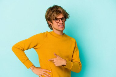 Makyajlı, mavi arka planda karaciğer ağrısı ve karın ağrısı olan beyaz bir genç..