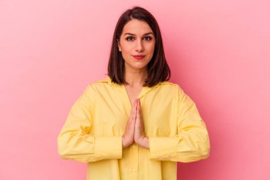 Pembe arka planda izole edilmiş genç beyaz kadın dua ediyor, bağlılık gösteriyor, dindar biri ilahi ilham arıyor..