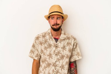 Beyaz arka planda izole edilmiş yazlık giysiler giyen Kafkasyalı genç bir adam kafası karışmış ve kendinden emin değil..