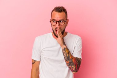 Pembe arka planda dövmeleri olan beyaz bir adam gizli bir sıcak fren haberinden bahsediyor.