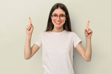 Sarı arka planda izole edilmiş genç beyaz kadın iki parmağı da boş bir alan gösteriyor..