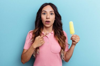 Dondurma tutan genç Latin kadın mavi arka planda izole edilmiş.