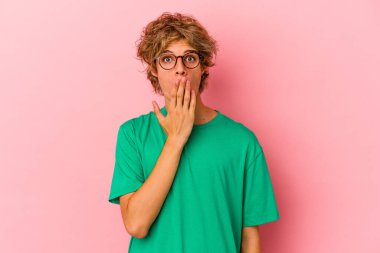 Pembe arka planda soyutlanmış, ağzı ellerle kaplanmış, yeni bir şey keşfetmeye hevesli beyaz bir genç..