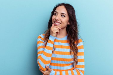 Mavi arka planda izole edilmiş genç Meksikalı kadın rahatça fotokopi odasına bakan bir şey düşünüyor..