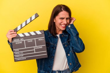 Sarı arka planda izole edilmiş, elleri ve kulakları olan genç beyaz bir kadın..