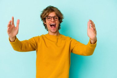 Mavi arka planda izole edilmiş, zaferi veya başarıyı kutlayan beyaz bir genç, şaşırmış ve şok olmuştu..